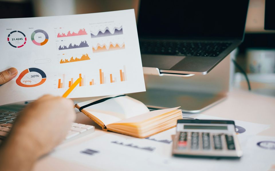 Printed charts being analysed beside a calculator and notebook