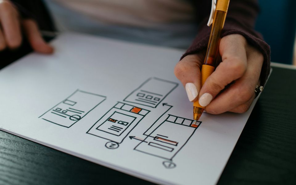 A hand sketching page layouts with a pen